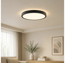 Modern rund LED-taklampa med svart ram i ett ljust vardagsrum.