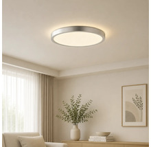 Rund LED-taklampa med metallram, monterad i ett ljust tak i ett modernt inrett vardagsrum.