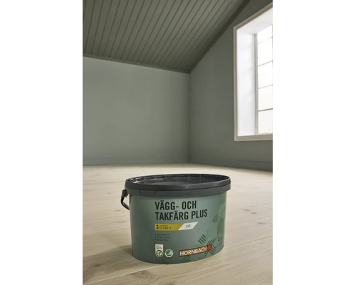 En hink Hornbach vägg- och takfärg Plus vit, Hornbach Logo, i ett ljust, organiserat rum med trägolv.