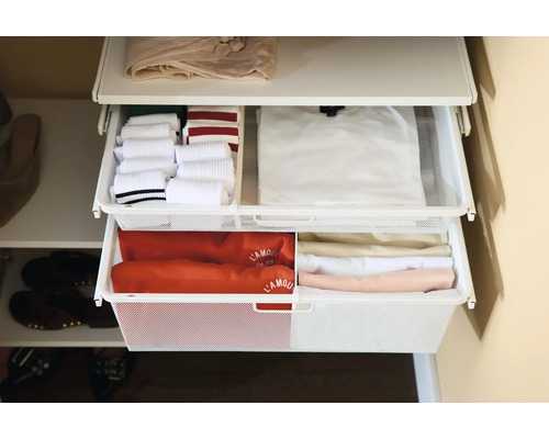 Organiserad garderob med två utdragbara trådkorgar i metallnät fyllda med prydligt vikta kläder som strumpor och t-shirts.