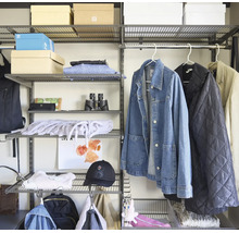 Modulärt hyllsystem i metall med gallerhyllor, klädstång och Adidas Logo på en låda, organiserat med kläder och accessoarer.