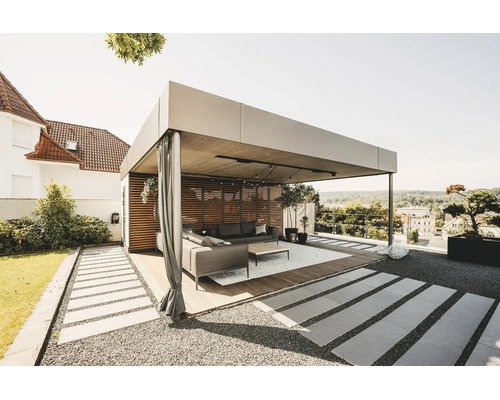 Modern, ljus pergola i metall med trälamellvägg, gardiner och loungemöbler på en träterrass i trädgården.
