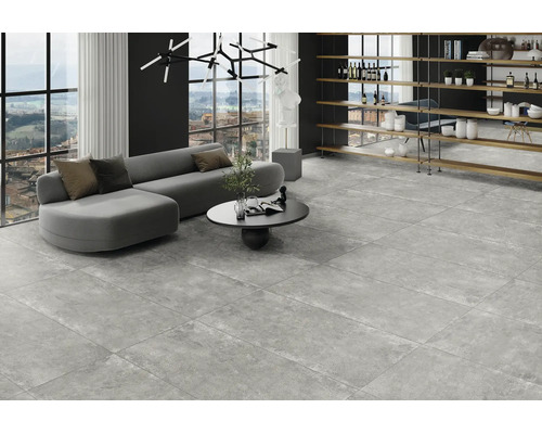 Modernt vardagsrum med stora grå golvplattor i granitkeramik med betonglook, grå soffa och stora fönster.