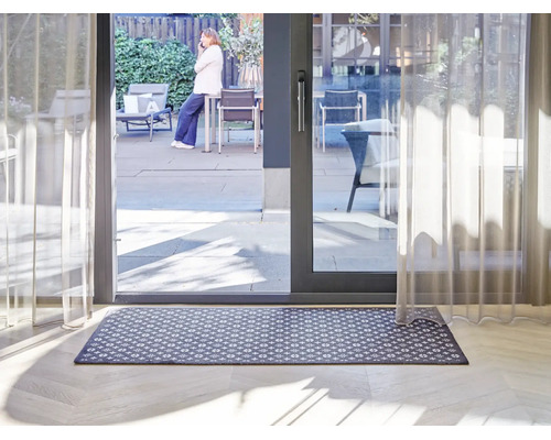 Rektangulär dörrmatta med grafiskt mönster framför en terrassdörr i ett ljust, modernt inrett rum.