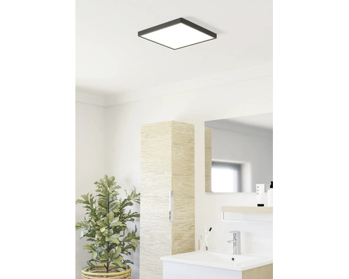 Ljust badrum med kvadratisk LED-taklampa, modernt tvättställ, högskåp i trädekor och krukväxt.