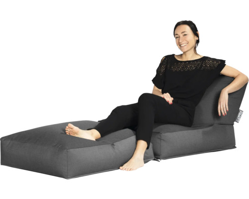 Tvådelat loungeset med sittsäckar bestående av en fåtölj med ryggstöd och en fotpall, där en kvinna sitter.