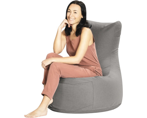 En kvinna som sitter i en grå sittsäck med högt ryggstöd av textil.
