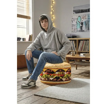 En tonåring sitter på en rund sittpuff formad som en hamburgare i ett ljust rum med trägolv.