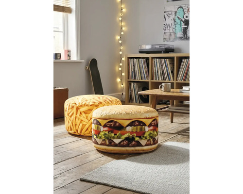 Två runda golvkuddar med hamburgar- och pommes frites-motiv i ett ljust vardagsrum på trägolv bredvid en hylla.