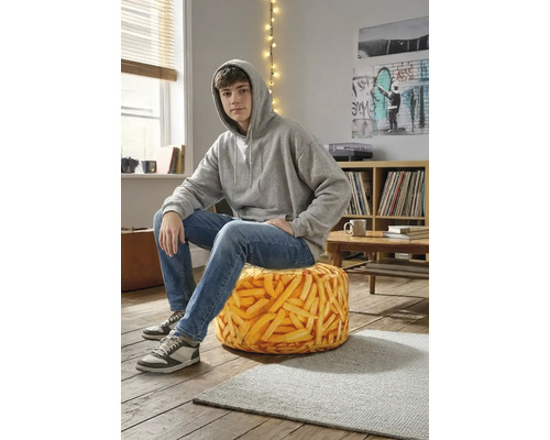 Tonåring som sitter på en rund saccosäck med realistiskt pommes frites-mönster i ett modernt rum med trägolv.