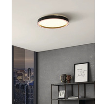 Rund LED-taklampa med svart hölje i ett modernt inrett rum med grå vägg och fönster med stadsutsikt.