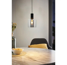 Modern taklampa med en cylindrisk glasskärm och svart metallfäste ovanför ett matbord i marmorlook.