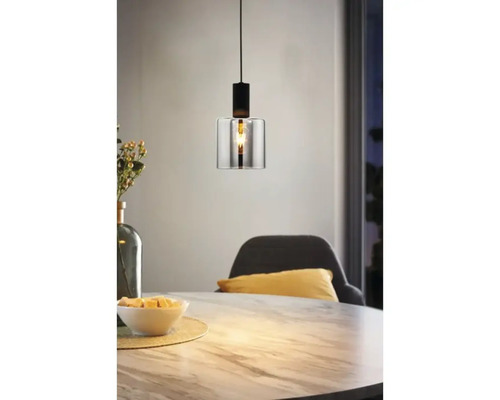 Modern taklampa med en cylindrisk glasskärm och svart metallfäste ovanför ett matbord i marmorlook.