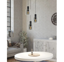 Trelågig taklampa med glasskärmar i ett ljust vardagsrum med vit tegelvägg, soffa och soffbord i industriell stil.