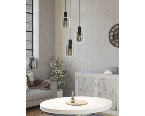 Trelågig taklampa med glasskärmar i ett ljust vardagsrum med vit tegelvägg, soffa och soffbord i industriell stil.
