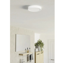 Rund platt LED-taklampa i ett ljust modernt badrum med spegel, hylla och växt.