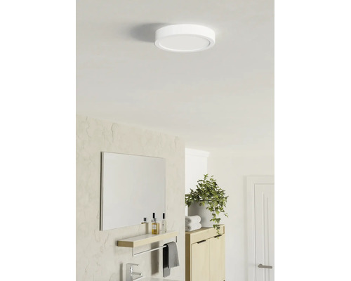 Rund platt LED-taklampa i ett ljust modernt badrum med spegel, hylla och växt.