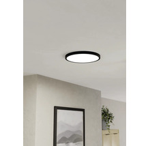 Platt, rund LED-taklampa med svart ram, monterad i taket i ett ljust vardagsrum.