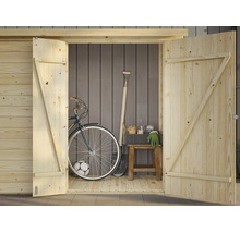 Rymlig trädgårdsstuga i ljust trä med öppna dubbeldörrar. Inuti finns en cykel, en spade, en pall och trädgårdsredskap.