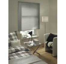 Modernt rum med silverfärgad persienn i aluminium, rutig säng, vitt sidobord och fåtölj.