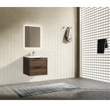 Modern kommod med tvättställ i träimitation, vitt handfat och en spegel med belysning i ett ljust badrum med strukturerade väggar.