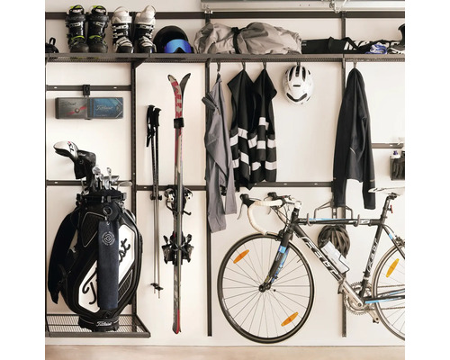 Organiserat hyllsystem för garage med väggfästen för sportutrustning såsom skidor, golfbag, cykel och kläder.