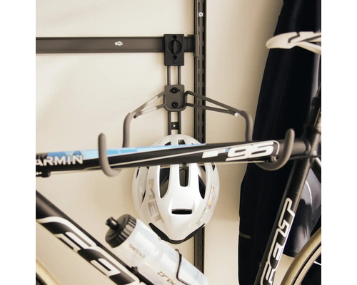 Väggfäste för cykel på skena med hängande cykelhjälm och racercykel