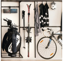Organiserad sportutrustning med väggfäste för golfbag, skidor, cykel och sportkläder i ett städat utrymme.
