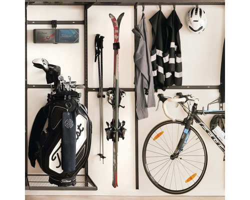 Organiserad sportutrustning med väggfäste för golfbag, skidor, cykel och sportkläder i ett städat utrymme.