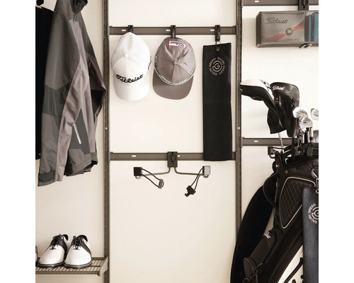 Väggsystem för att organisera golfutrustning med krokar för kepsar och handdukar, samt hyllor för golfskor och en golfbag på väggen.