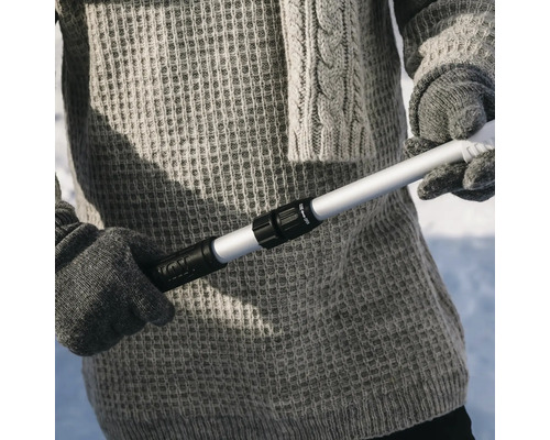 Person i stickade kläder håller i en utdragbar teleskopstång av aluminium med svart vridlås.