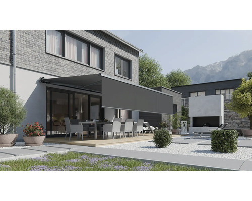Modern terrassmarkis med utdragbar volang på ett hus med tegelvägg och trädgård med sittgrupp.