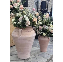 Två stora terrakottaamforer med blomsterarrangemang på ett stengolv.