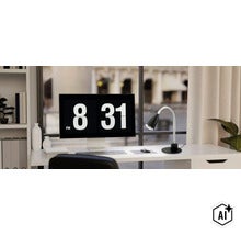 Modern skrivbordslampa med flexibel arm på ett skrivbord framför ett fönster bredvid en datorskärm i ett ljust kontor. (Image AI modified or generated)
