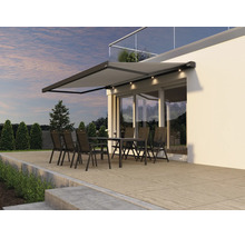 Modern terrassmarkis med inbyggd LED belysning över en sittgrupp på en terrass framför en husfasad.