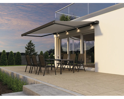 Modern terrassmarkis med inbyggd LED belysning över en sittgrupp på en terrass framför en husfasad.