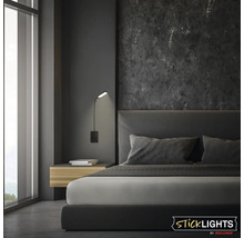 Modern väggmonterad läslampa från Sticklights by Briloner i ett elegant sovrum med mörk marmorvägg och stoppad säng.
