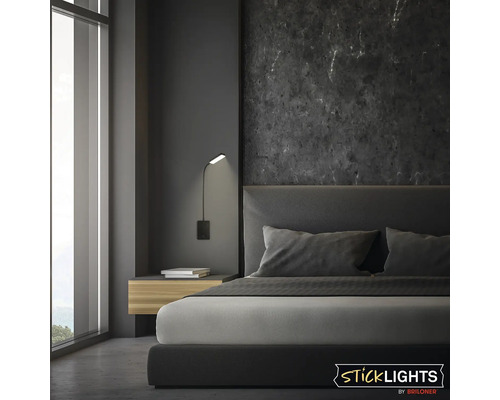Modern väggmonterad läslampa från Sticklights by Briloner i ett elegant sovrum med mörk marmorvägg och stoppad säng.