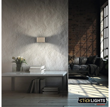 Modern LED vägglampa med upp och ner ljuseffekt på en strukturerad vägg i en industriell inredning.