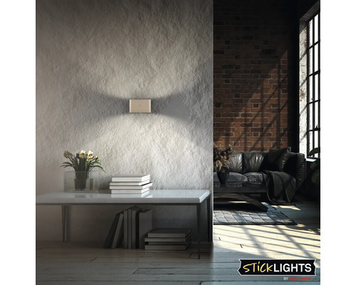 Modern LED vägglampa med upp och ner ljuseffekt på en strukturerad vägg i en industriell inredning.