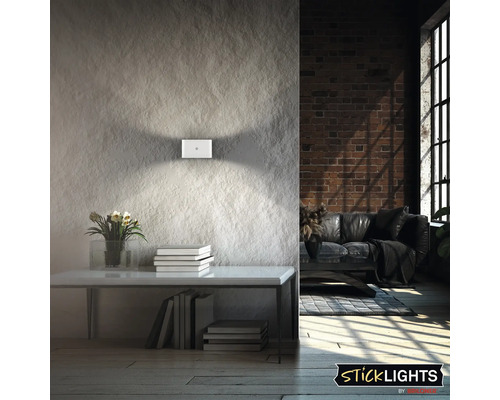 Modern LED vägglampa med ljuskäglor uppåt och nedåt på en strukturerad vägg i ett stilrent vardagsrum.