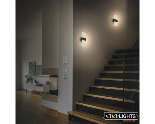 Två moderna LED vägglampor med rörelsesensor lyser stämningsfullt upp trappan i ett vardagsrum.