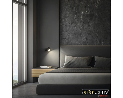 Modern sovrumsinredning med en väggmonterad Sticklights by Briloner LED-lampa ovanför ett nattduksbord.