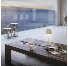 Modern LED bordslampa på ett träbord med en kaffekopp och en tidning på en terrass med havsutsikt.