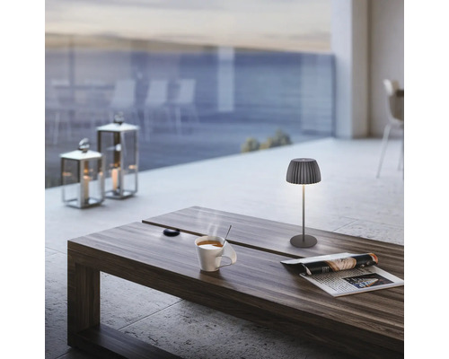 Modern trådlös LED-bordslampa på ett träbord med kaffekopp och tidning på en terrass.