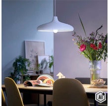 Modern taklampa i en ombonad matsal ovanför ett träbord med en blomsterbukett i en glasvas. (Image AI modified or generated)
