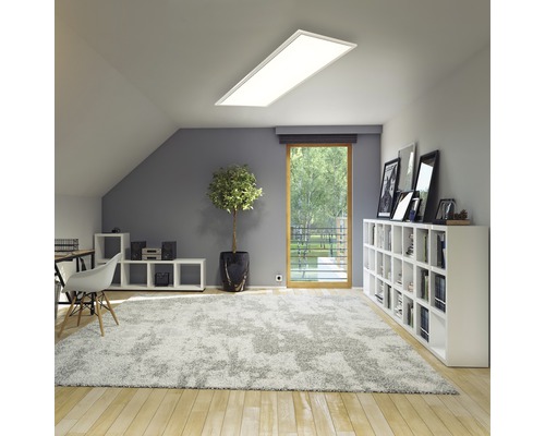 Ljust vindsrum med infälld taklampa, matta och vita möbler.