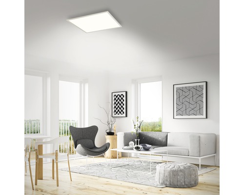 Ljust vardagsrum med modern infälld taklampa, soffa, fåtölj och dekoration