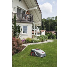 Robotgräsklippare på en gräsmatta framför ett bostadshus