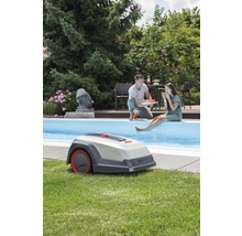 Robotgräsklippare i trädgård med pool och avslappnade personer